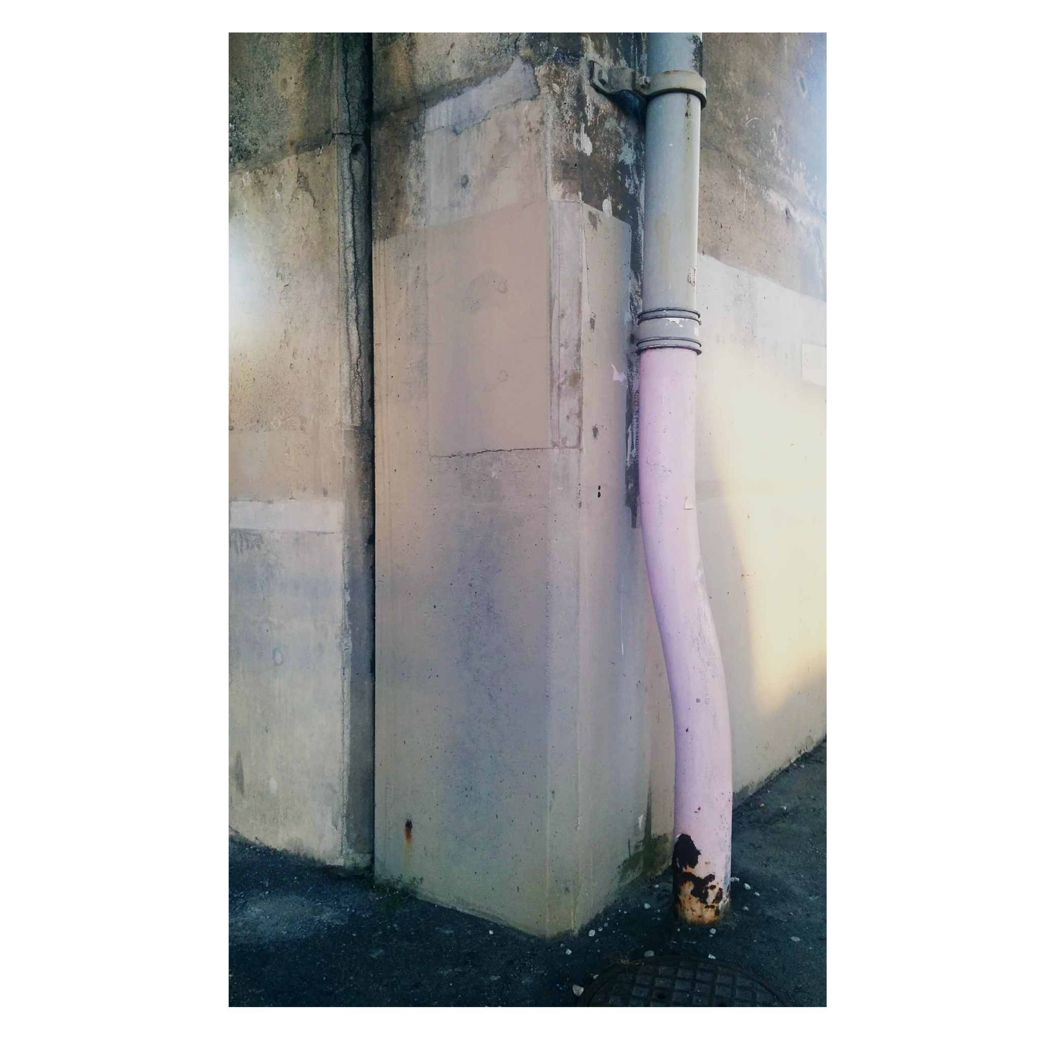 pink pipe next to old cement wall
